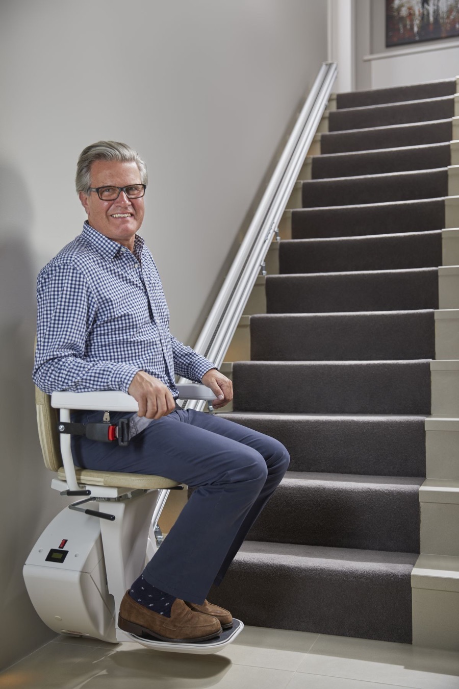 Sitzlift an einer geraden Treppe, die Schiene verläuft dicht an der Wand